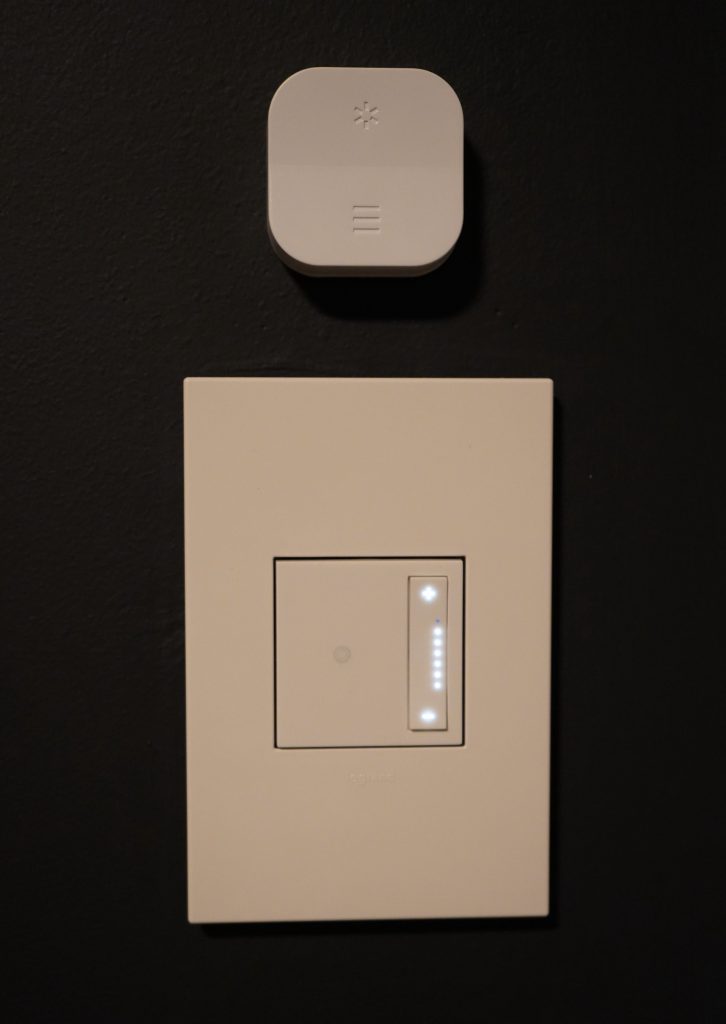 Small wireless control mounted above a wall light switch.