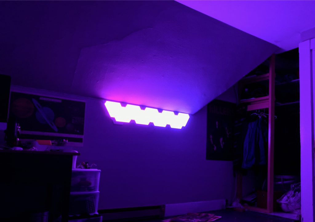 Nanoleaf panels lighting the wall above a television.
